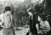 Pittsburgh Silent Film Festival Brings Classic Movies to Theaters This September Black-and-white film still from Sparrows showing Mary Pickford protectively shielding a child as an older boy in suspenders and a hat gesticulates in front of them outdoors.