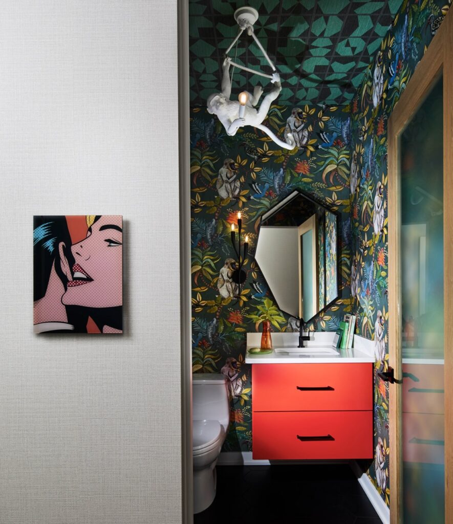 Bold powder room with monkey wallpaper, red vanity, and pop art