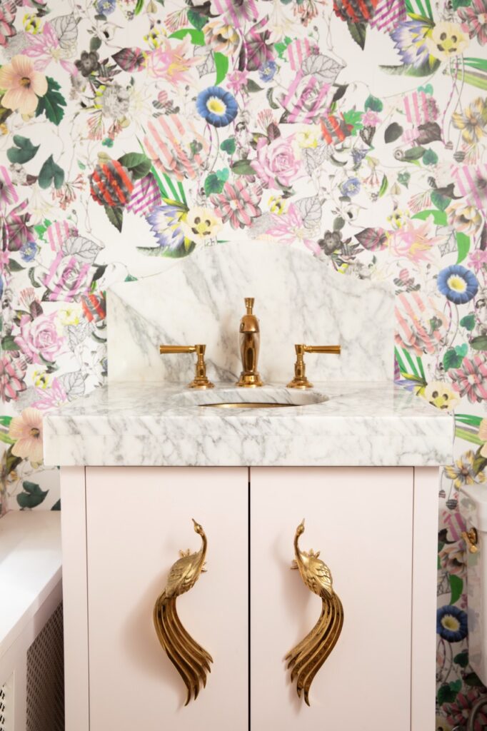 Bold powder room vanity with floral wallpaper and gold peacock pulls