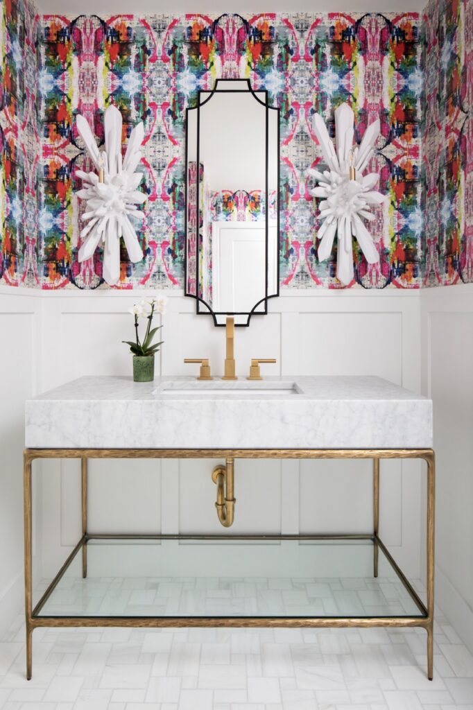 Bold powder room with colorful wallpaper, marble vanity, and gold accents.