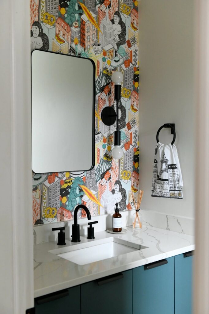 Bold powder room with cityscape wallpaper, black faucet, and teal vanity.