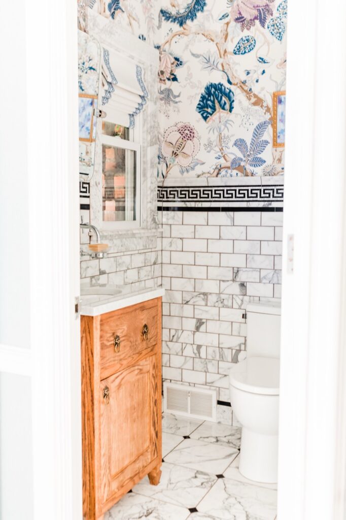 Bold powder room with floral wallpaper, subway tile, and wood vanity
