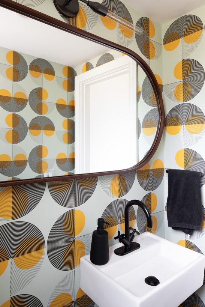 Bold powder room with geometric wallpaper, black faucet, and white sink