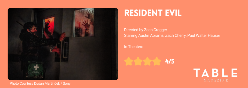 An orange rating card for the Resident Evil movie with a photo from the film of Austin trying to keep a door shut between him and the zombies. The rating card gives a 4/5 star rating.