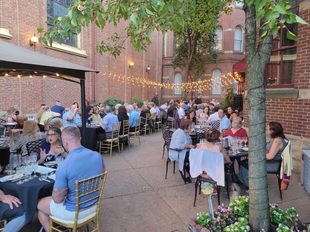 Outdoor dining in Pittsburgh: people enjoy dinner at tables under string lights.
