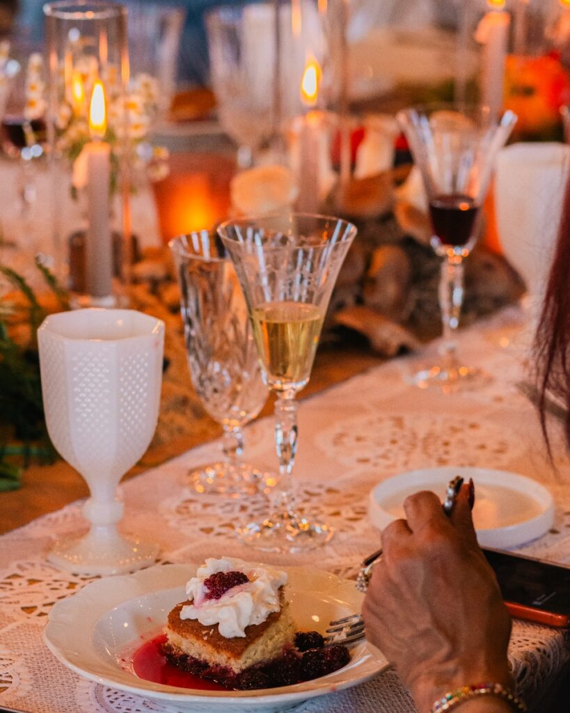 A guest enjoying a slice of Busy Day Cake at a candlelit table set with fine glassware.