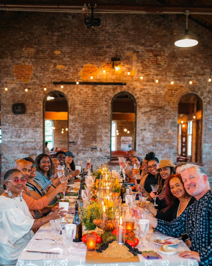 Event attendees raising their glasses for a toast around a brightly lit, decorated dining table.