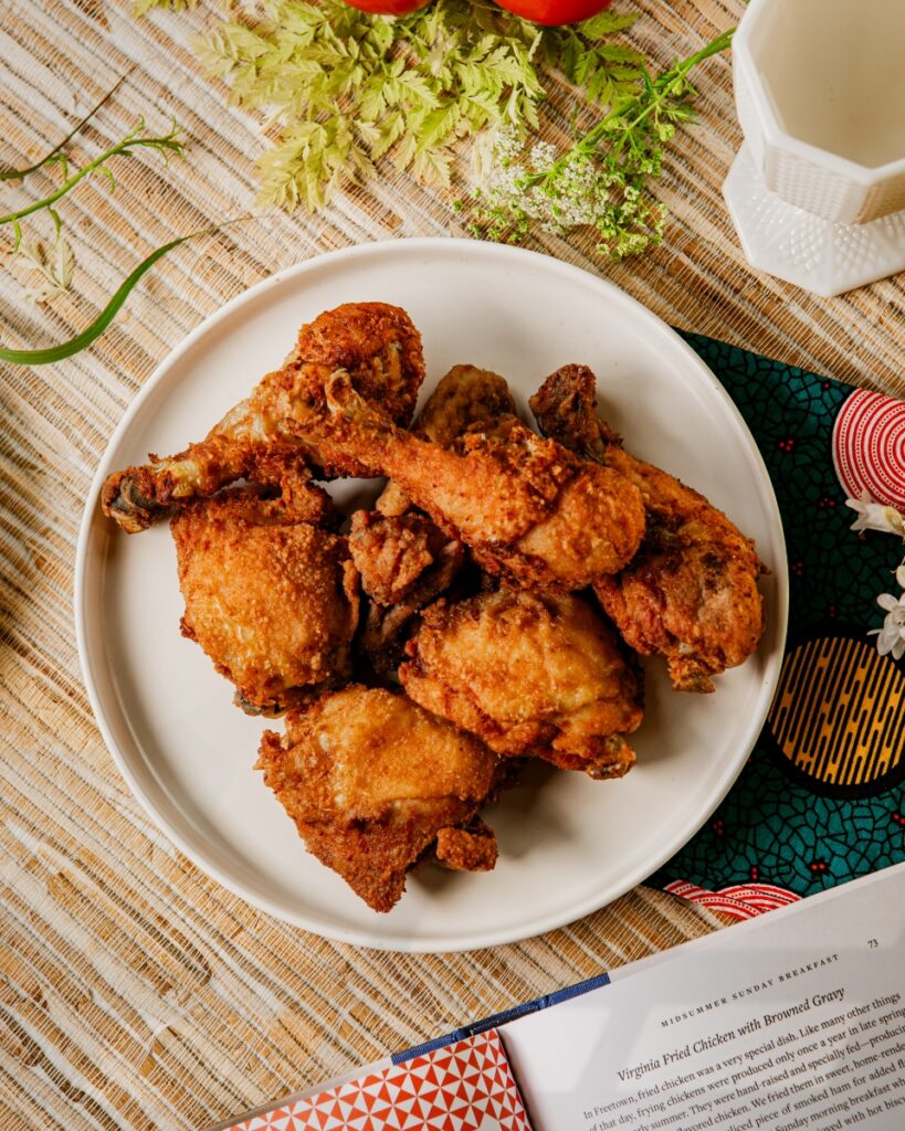Crispy golden Virginia fried chicken served on a white ceramic plate over an African patterned napkin.