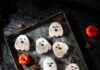 Pumpkin Brown Butter Shortbread Ghost Cookies Ghost-shaped pumpkin brown butter shortbread cookies dusted with powdered sugar and decorated with melted chocolate faces, arranged on a vintage tray with mini pumpkins and star anise.