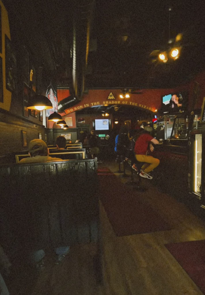 Interior of a dimly lit, alternative bar with patrons seated at booths and the counter.