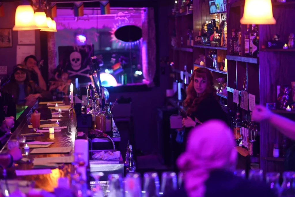 Woman serving drinks at a dimly lit bar with skull decor, Pittsburgh goth shop