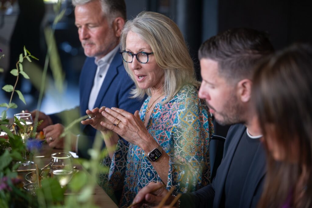 Woman speaks at a table with local leaders, discussing Pittsburgh's welcoming initiatives.