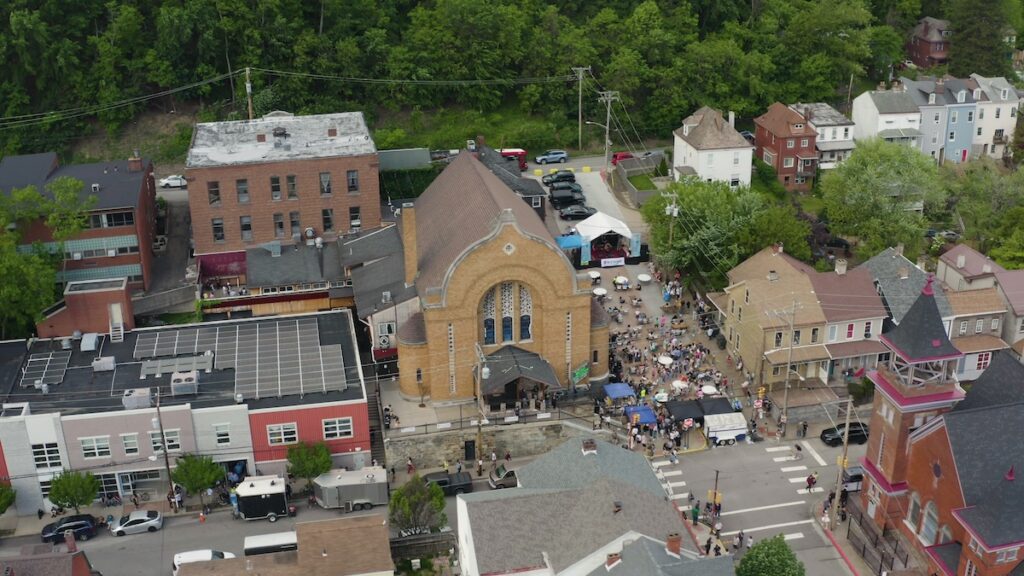 Aerial view of a street festival in front of a large, ornate building.
