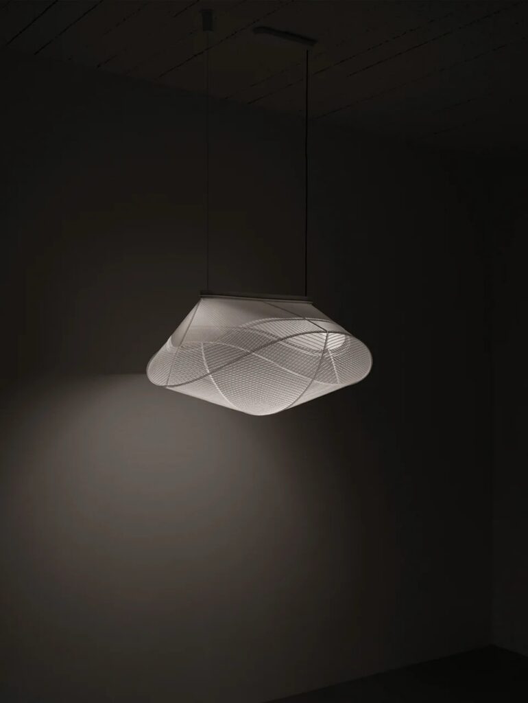 A 3D printed light in a white color by LightMass reflecting light onto a black wall.