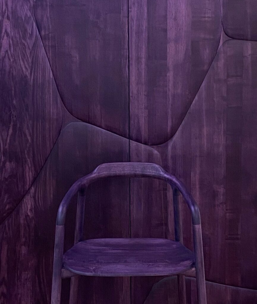 A purple chair by  Franck Genser against a purple stone wall.