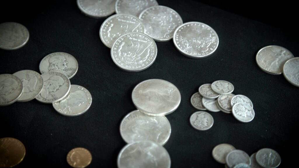 Collection of silver coins, including Morgan dollars and Mercury dimes, on a dark surface.