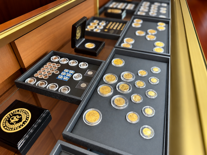 Collection of gold coins and collectible currency displayed in a museum case.