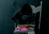 Horror and Thriller Books to Read From Pittsburgh Authors Stack of horror and thriller books by Pittsburgh authors on a chair with a crow.
