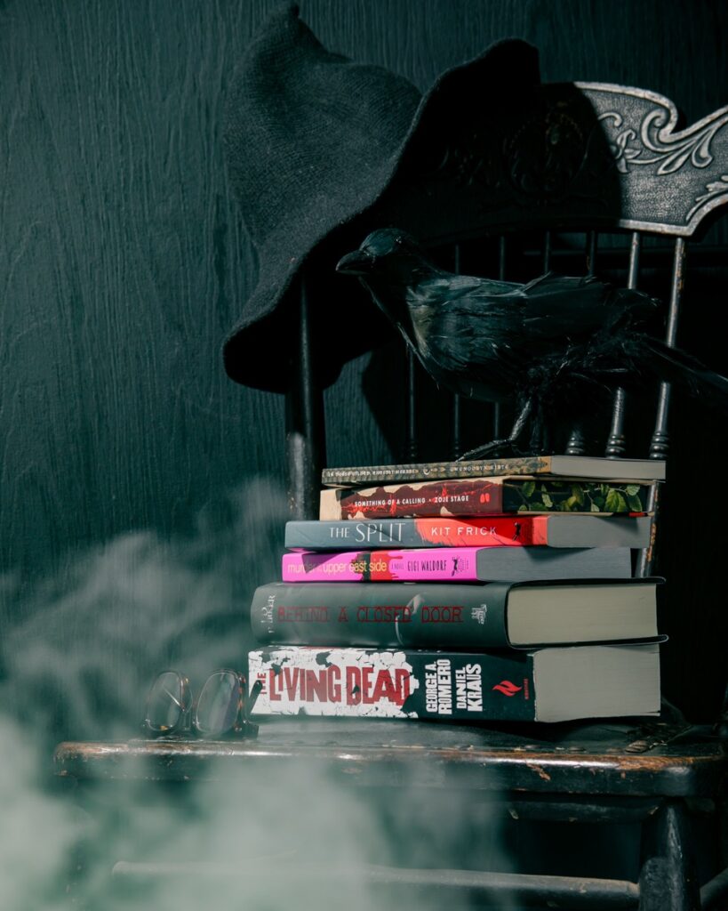 Stack of horror books with a raven and hat, for pittsburgh horror authors.