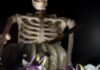 Poison Apple Punch: A Color-Changing Halloween Cocktail Poison Apple Punch in a two glasses topped with dry ice fog and purple steeped apple slices in front of a skeleton.