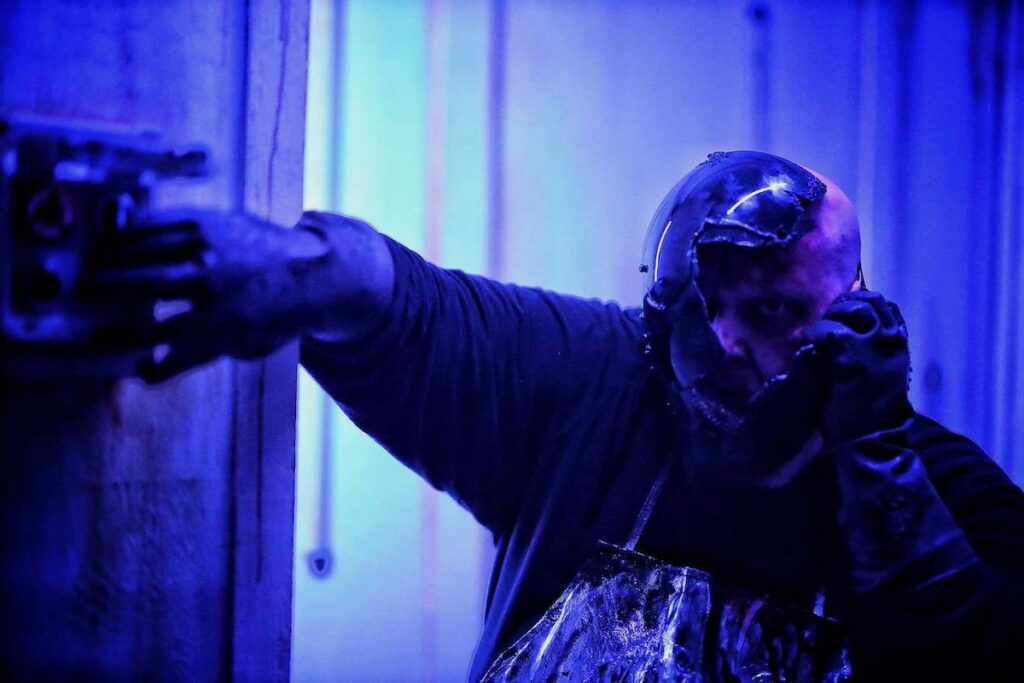 Scary masked figure in blue light at Portals of Fear haunted attraction.