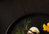 Deviled Egg Spiders: An Easy Halloween Appetizer with Bacon and Scallions Deviled eggs topped with black olive spiders on a Halloween serving platter.