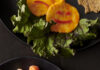 Spooky Halloween Charcuterie Board with Carrot Witch Fingers and Cheese Ghosts Carrot sticks on a black plate with red fingernails on them below two slices of cheese made to look like jack o lanterns.