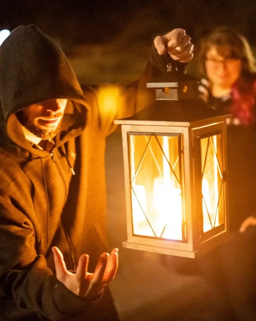 Man holding a lantern on a Pittsburgh ghost tour at night