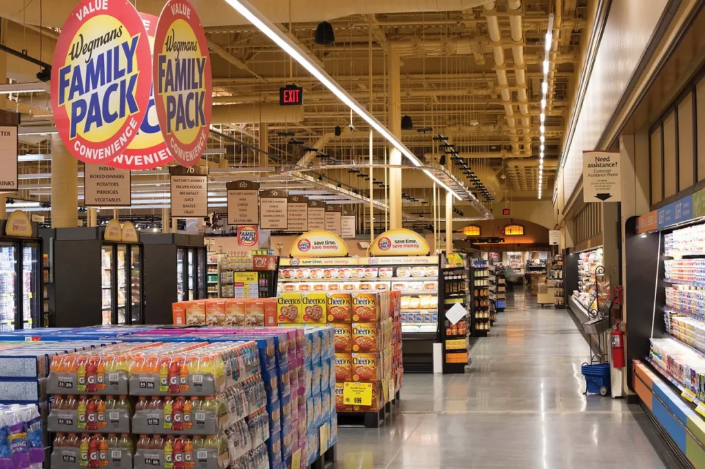 Wegmans grocery store aisle with "Family Pack" signs and colorful product displays