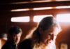 Collier’s Cuts: Up Close and Deceptive With Fraudster Elizabeth Holmes in ‘You Can See Everything’ Elizabeth Holmes stands in her kitchen with Nathan Fielder behind her in the background.